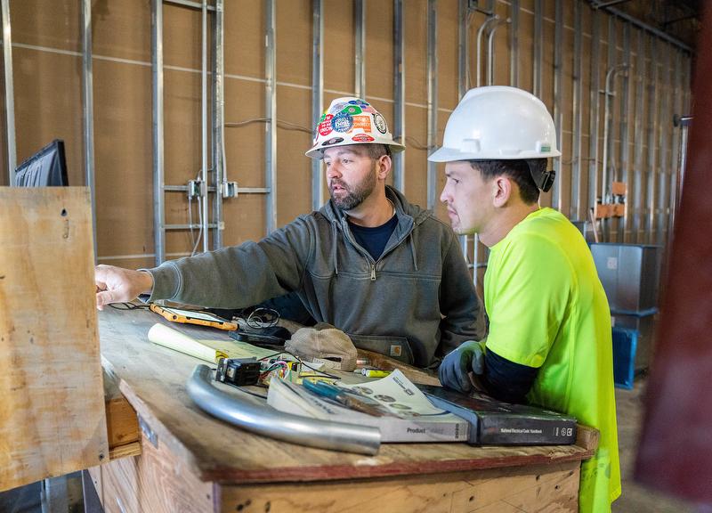 McElroy Electric technicians review electronic plans on a jobsite.